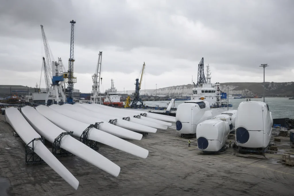 Navire de pose de fondations à côté d'une éolienne en construction, en mer, sous un ciel gris.