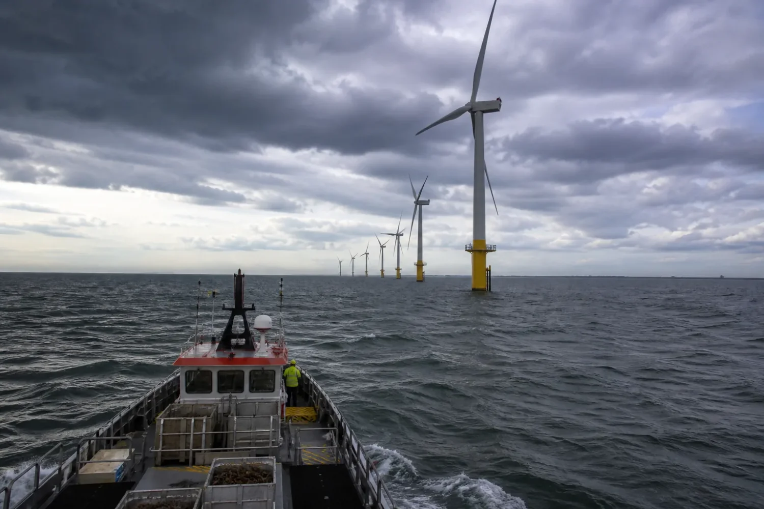 Rangée d'éoliennes en mer vues depuis une falaise de craie sur la côte normande.
