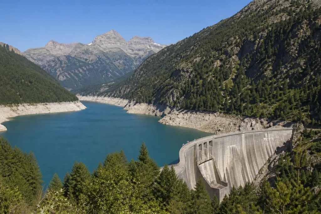 Torrent de montagne alimenté par la fonte glaciaire, roches et végétation rase, vallée alpine en arrière-plan